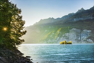 Last light over Lake Walen with the small chive island in the turquoise water and mountain range