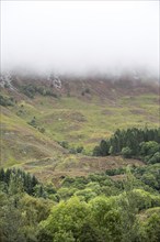 Rain cloud forming thick fog descending from steep hillside of Bidean nam Bian in Glen Coe, Argyll,