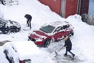 Man and woman shovelling snow on car park, car, car, snowed in, fresh snow, heavy snowfall, snow