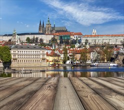 Wooden planks vith view of Prague Charles bridge over Vltava river and Gradchany (Prague Castle)