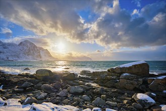 Beach of Norwegian sea on rocky coast in fjord on sunset in winter. Vareid beach, Lofoten islands,