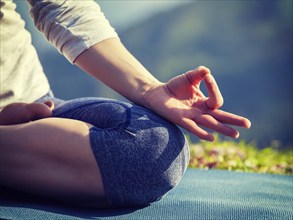 Close up of woman in Padmasana yoga lotus pose with chin mudra outdoors with copyspace. Vintage