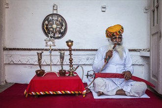 JODHPUR, INDIA, NOVEMBER 26, 2012: Old Indian man smokes hookah (waterpipe) in Mehrangarh fort. The