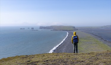 Tourist on rocky coast, view over Reynisfjara beach, black sand beach, Vik, South Iceland, Iceland,