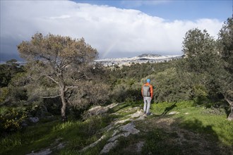 Tourist looking over the city with rainbow, Philopappos Hill, in the evening light, Athens, Attica,