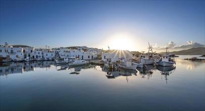 Fishing boats in the harbour of Naoussa at sunset, reflected in the sea, Sun star, White Cycladic