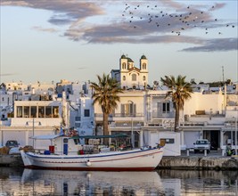 View of Naoussa, Fishing boats in the harbour at sunset, reflected in the sea, White Cycladic