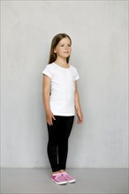 Cute young child with long hair in white t-shirt and black sweatpants posing