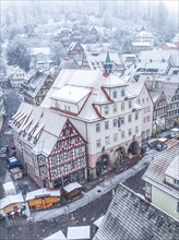 Drone shot of a wintery snowy market square with historic buildings, Black Forest, Calw, Germany,