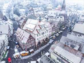 Snow-covered market square with half-timbered houses photographed from above during a wintry day,