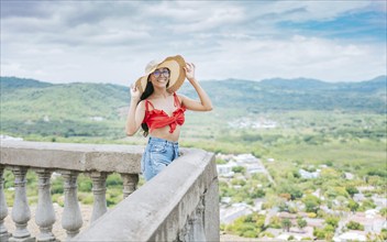 Portrait of beautiful tourist girl in a viewpoint. Happy vacationer woman in hat on a viewpoint.