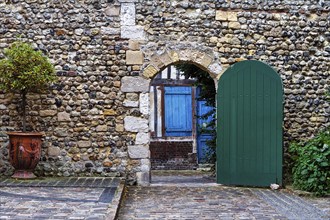 View through gate with green door on traditional stone house with blue door, Old Town, Honfleur,