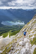 Via ferrata over the Riffelscharte, hiker in the mountains, view of Eibsee lake and Werdenfelser