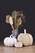 Seasonal fall decoration with boho style knitted beige pumpkin and gray stone pumpkin on dark