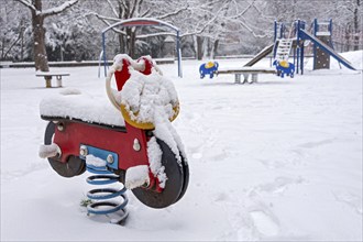 Seesaw motorbike, spring seesaw for children, snow on playground in winter, Nußbaumpark, Altstadt,