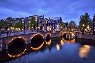 Night view of Amterdam cityscape with canal, bridge and medieval houses in the evening twilight