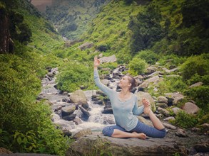 Yoga outdoors, young sporty fit woman doing stretching yoga asana Eka pada rajakapotasana,