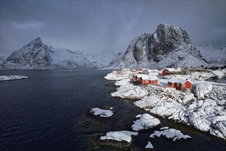 Iconic Hamnoy fishing village on Lofoten Islands, Norway with red rorbu houses. With falling snow