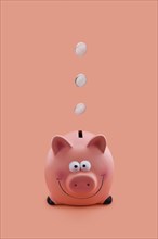 Pink piggy bank with coins falling down