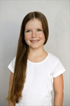 Cute young child with long hair in white t-shirt and black sweatpants posing