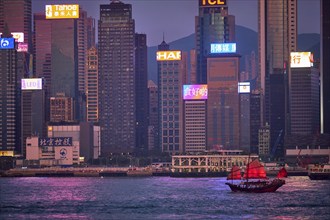 HONG KONG, CHINA, MAY 1, 2018: Tourist junk boat ferry with red sails and Hong Kong skyline