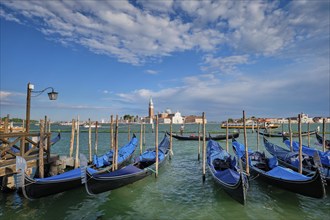 VENICE, ITALY, JUNE 27, 2018: Gondolas and gondolier in lagoon of Venice by Saint Mark (San Marco)