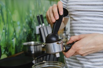 Closeup view of female hands making ground coffee in coffee machine