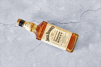 April 13, 2021, Minsk, Belarus, Bottle of Jack Daniel's Honey laying on cracked grey concrete