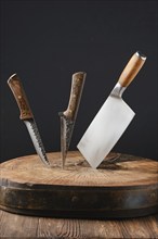 Cleaver and two meat knives sticking out of wooden stump