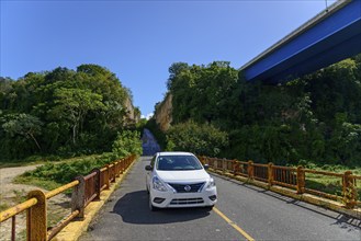 Car parked in the sun on one of the two bridges over the Chavon River surrounded by lush