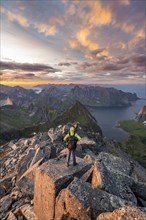 View over mountain top and sea, dramatic sunset, mountaineers at Hermannsdalstinden peak, with