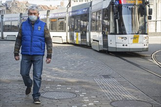 Tram and man wearing medical face mask due to 2020 COVID-19, coronavirus, corona virus pandemic