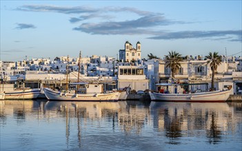 View of Naoussa, Fishing boats in the harbour at sunset, reflected in the sea, White Cycladic