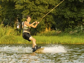 Young man riding wakeboard in lake, Leisure and water sports, Germany, Europe