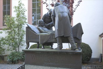 Sculpture and memorial to Werner Senger, three, figures, bed, lie, help, care, sick person,