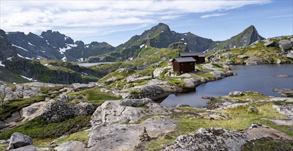 Mountain hut Munkebu hut by a small lake, mountain landscape with rocky peaks and lakes,