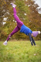 Fitness enthusiast woman practising handstand outside, surrounded by autumn colours, Gechingen,