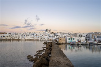 Harbour wall, view of the town of Naoussa and blue sea, at sunset, harbour with fishing boats and