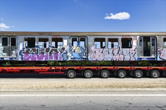 Heavy goods transport parked at the roadside, discarded train wagons, wagon with graffiti, detail,