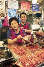 Korean woman and Korean man with a crab, Gwangjang market, traditional street market in Jongno-gu,