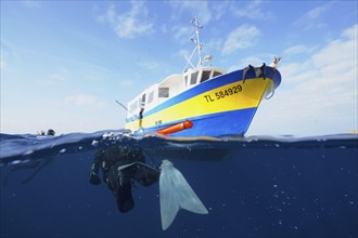 Diver swims back to the dive boat. Half and half shot. Dive site Giens Peninsula, Côte dAzur,