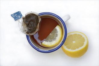 Black tea in cup with lemon slice and infusion bag