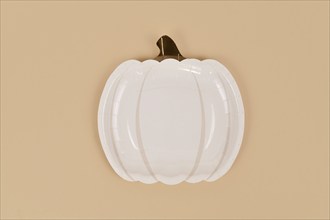 Simple pumpkin shaped party paper plate on beige background