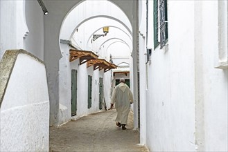 Moroccan Muslim man wearing traditional Islamic djellaba, jillaba walking in medina of the city