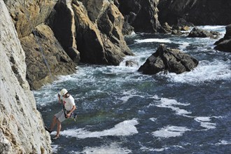 Rock climber climbing cliff face at the pointe de Pen-Hir, Finistère, Brittany, France, Europe