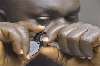 Diamond dealer looking at a diamond through a magnifying glass, Koidu, Koidu-Sefadu, Kono District,