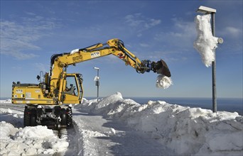 Two-way excavator clears the tracks of snow at Brocken railway station in the Harz mountains,