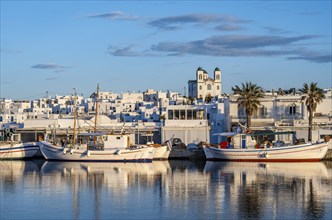 View of Naoussa, Fishing boats in the harbour at sunset, reflected in the sea, White Cycladic