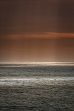 Sunbeams through cloud cover, sunlight glistening on the sea, evening sky, motion blur,