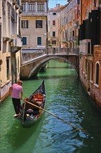 VENICE, ITALY, JULY 19, 2018: Narrow canal between colorful old houses with gondola boat with